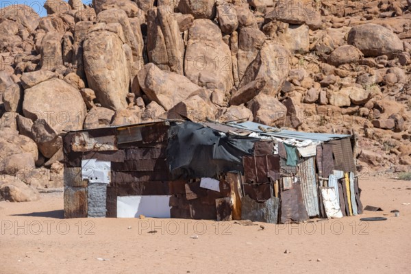 Simple poor huts made of corrugated iron and wood, desert landscape, barren landscape with hills of