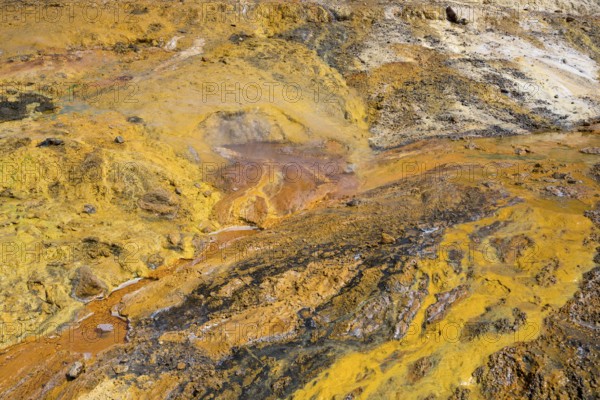 Colourful geothermal formation with yellow and orange earth tones and mineral-rich textures,