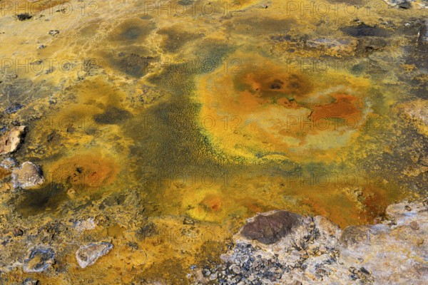 Mineral-rich geological formation in bright orange and yellow tones with rocky surface, geothermal