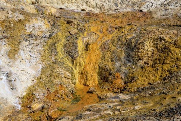Orange, steep geological formation with volcanic character and rocky texture, geothermal area,