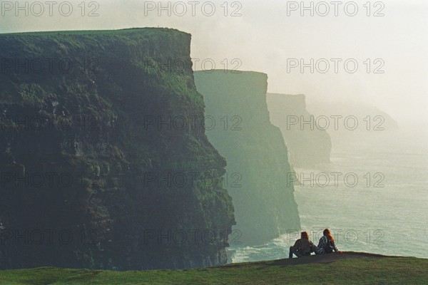 People on the edge of a cliff, there was no fence back then, Cliffs of Moher, County Clare,