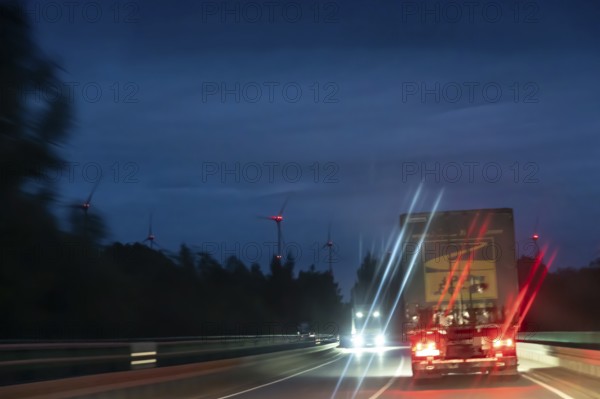 Truck on federal highway at night, wind turbine lights on the left, Schleswig-Holstein, Germany