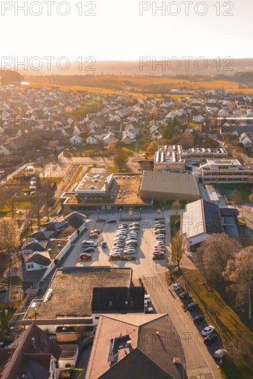 Aerial view of a village at sunset with parking lots and autumn landscape, sports center and