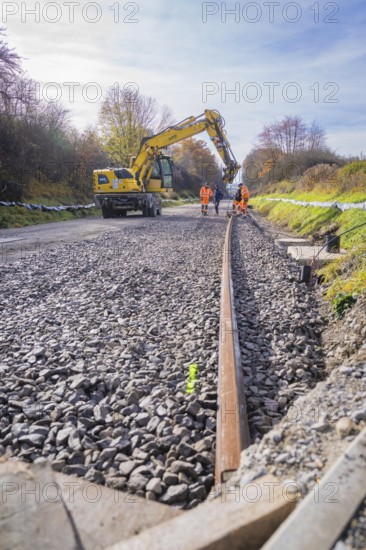 Crane aligning ballast on a construction site, workers watching, Hermann Hesse Railway track