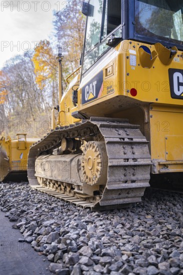 CAT chain tractor on gravel, area in autumn forest during construction, Hermann Hesse Railway track