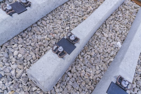 Detailed view of concrete sleepers and their metal fastenings on gravel, track construction of the