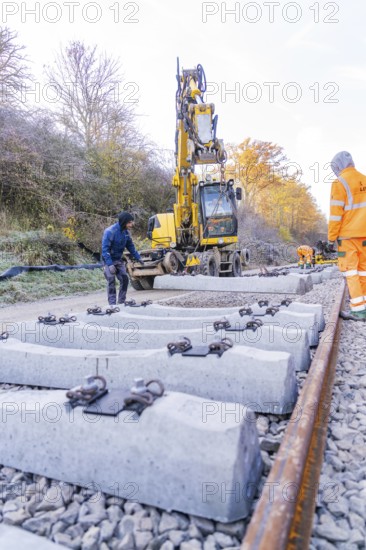 Workers and excavators install new rail ties in an autumn environment, Hermann Hesse Railway track