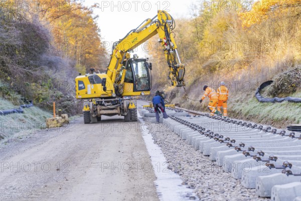 Workers and an excavator lay tracks in an autumn environment, track construction of the Hermann