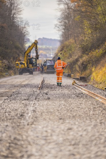 Road construction with construction workers and cranes on a gravel road in autumn, track