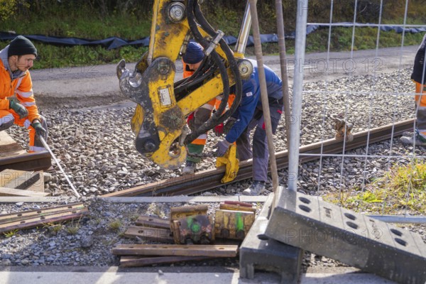 Construction workers install rails on a construction site with heavy equipment, Hermann Hesse