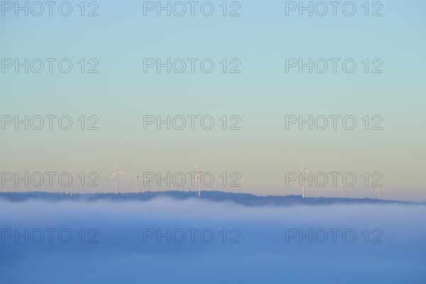 Wind turbines on a hill with fog in the foreground and blue sky, Miltenberg, Spessart, Bavaria,