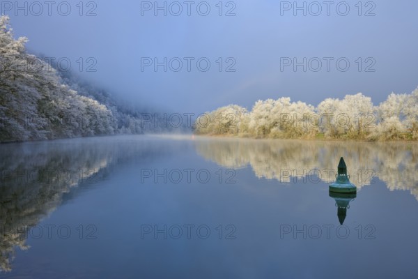 A green buoy on calm water, surrounded by snowy, reflecting trees, hoarfrost, winter, Boxtal,