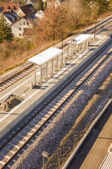 Station with platforms and tracks, surrounded by autumn leaves and houses, seen from a bird's eye