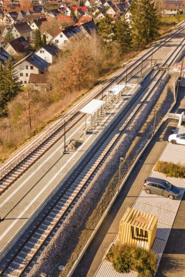 Aerial view of a small train station with parked cars surrounded by autumn vegetation and a