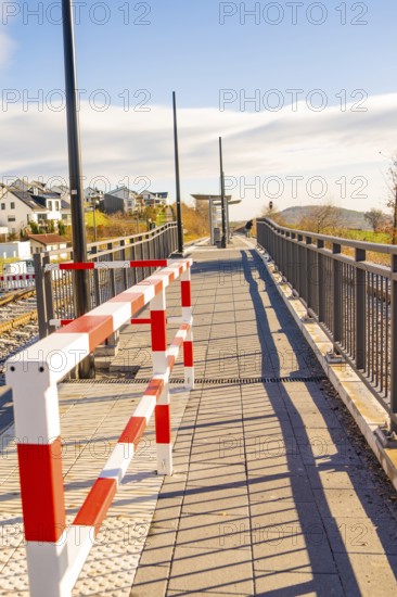 Footbridge with modern barrier and cast shadows in sunshine, new Hermann Hessebahn railway station,