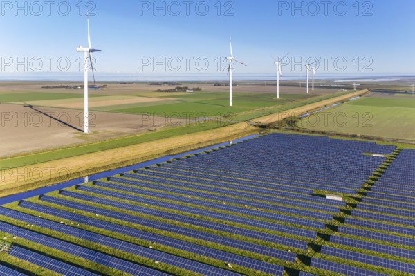 Aerial view over hybrid power plant combing solar photovoltaic modules and wind turbines, North