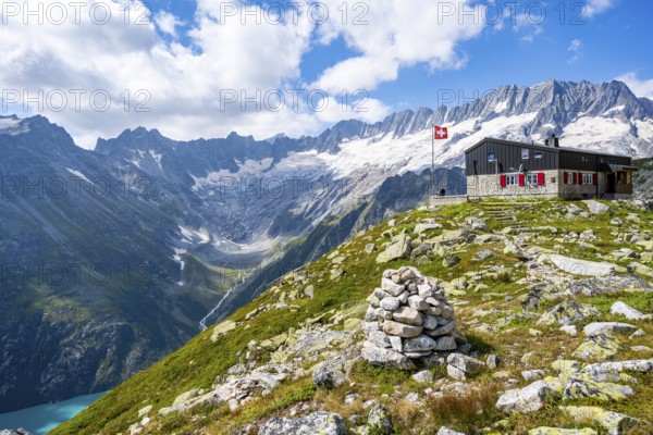 Mountain hut Bergseehütte with Swiss flag in picturesque mountain landscape, view of Damma Glacier