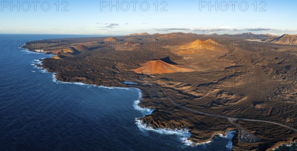 Coast with lava fields, volcanic landscape near Los Hervideros with red volcano Montaña Bermeja, in