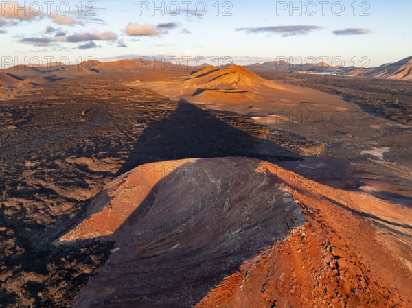 Picturesque volcanic landscape in evening light, red volcano Montaña Bermeja between lava fields,