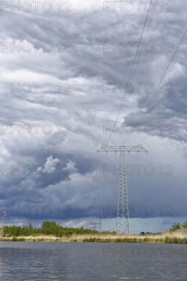 A large power pole in a vast landscape under dramatic clouds, Peenetal nature park Park,