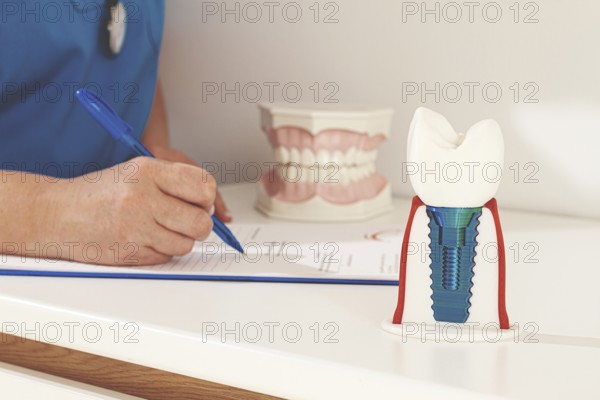 A dentist in a blue uniform studies patient information and prepares for treatment in a modern
