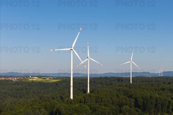 Wind power plants in a wooded area under a bright blue sky, near Schorndorf, Remstal,