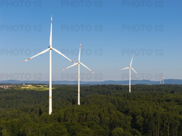 Several wind turbines stretch into the sky over an extensive forest area, near Schorndorf, Remstal,