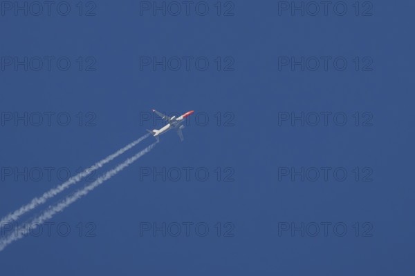 Boeing 737 jet passenger aircraft of Norwegian Air airlines flying in a blue sky with contrails or