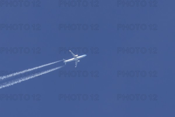 Jet passenger aircraft flying in a blue sky with contrails or vapour trails behind, England, United