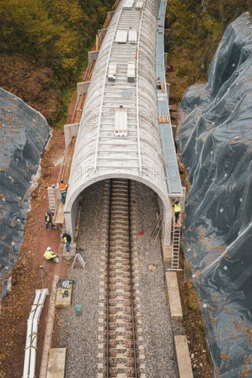 Close-up of tunnel construction site with workers and surrounding autumnal forests,