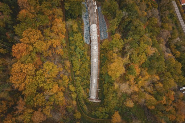 View from above of a tunnel under construction in a colorful forest, Hermann-Hesse-Bahn