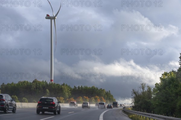 Tourist traffic on the A9 motorway during thunderstorms, a wind turbine in the back, Bavarian
