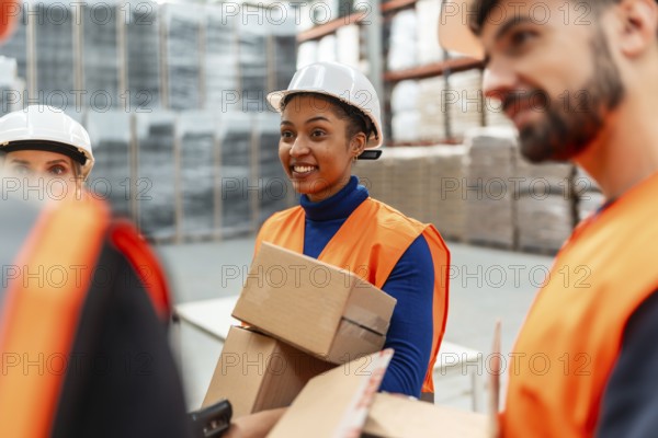 Diverse team of logistics workers wearing safety vests and hard hats, collaborating on picking and