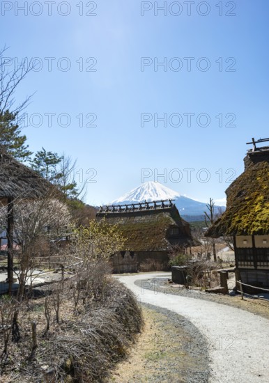Iyashinosato open-air museum, old Japanese village with traditional houses, at the back volcano Mt.