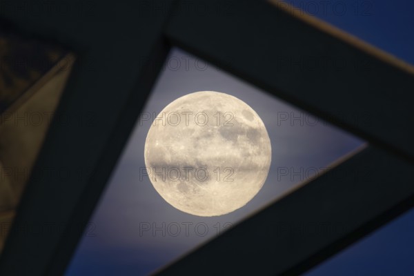 The full moon sweeps along the Frankfurt evening sky and passes the pillars of the rafter bridge,