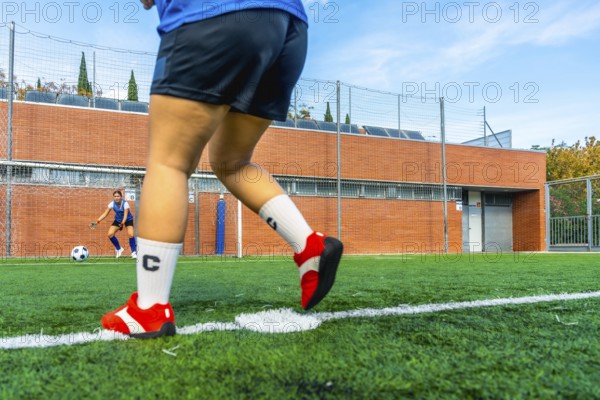 Football player preparing to shoot a penalty kick on an artificial turf field, with the opposing