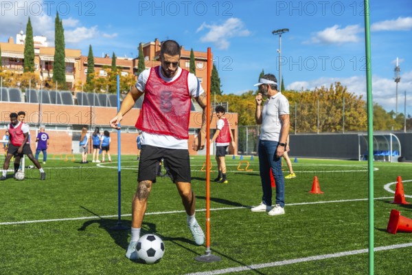 Soccer player is training on a professional artificial turf field, dribbling a ball through