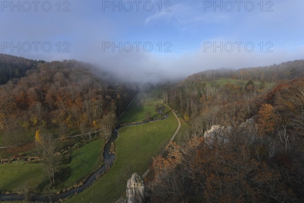Autumn landscape with rising fog over the Grosse Lauter river loop in Lautertal at sunrise. View