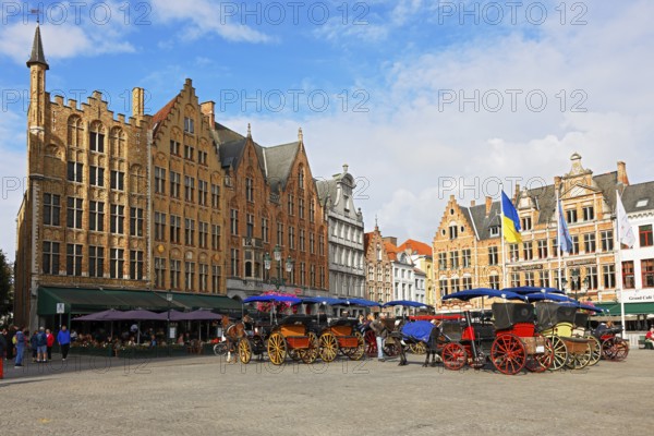 Historic houses on the market square in the old town of Bruges with horse-drawn carriages, Grote