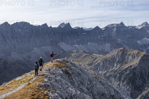 Hikers on the summit ridge of the Gamsjoch, behind rock faces of the Laliderer Spitze, eastern