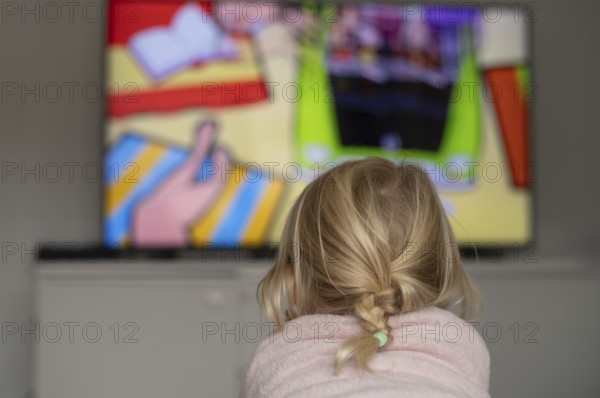 Child, girl, 4 years old, blonde, lying on sofa, watching TV, watching television, in front of