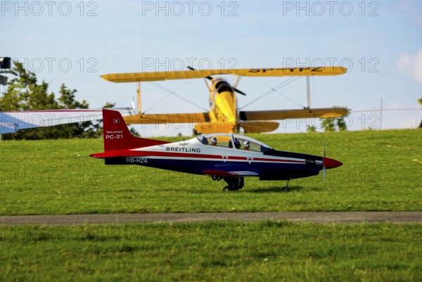 An RC model of a Pilatus PC-21 with advertising for the Swiss watch brand Breitling during a flight