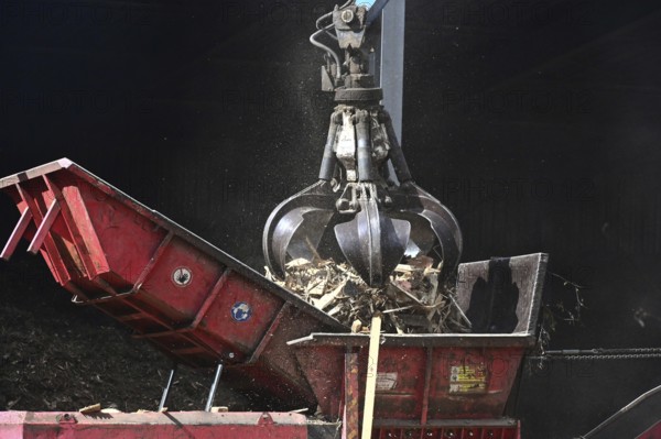 Loading crane with grab arm for loading wood waste for wood pellet production on the premises of