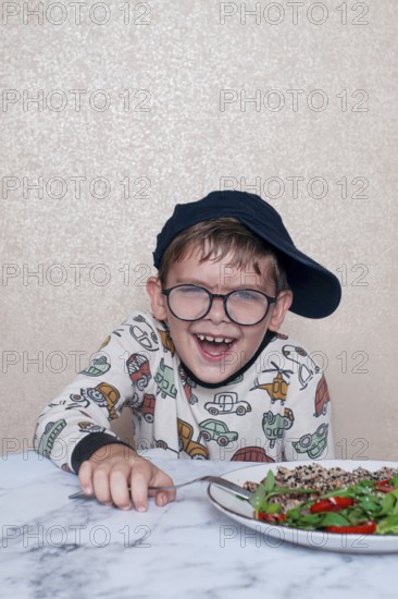 Child reacts dramatically to a salad served on a marble table at home during lunchtime, A little
