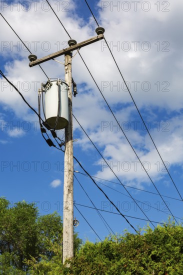 Electricity transformer, high voltage transmission wires, internet, telephone cables attached to