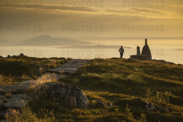 Woman standing next to cairn and looking at the sea, Rørsethornet stone staircase, with 3292 steps