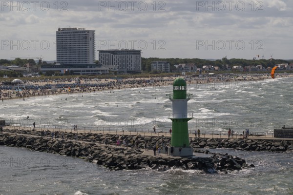 Green and white lighthouse, pier light Westmole in front of lively beach and hotels in the