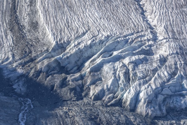 Intricate patterns of ice and rock are showcased in this stunning glacial landscape, revealing the