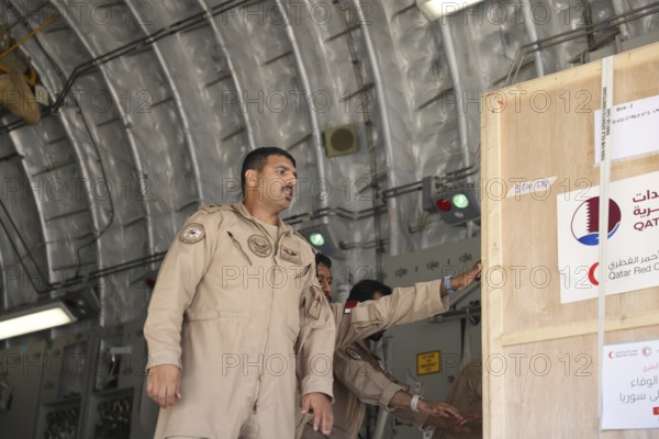 Members of the Qatari Air Force unload humanitarian aid supplies from a transport aircraft at