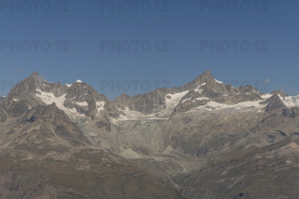 Majestic mountain peak rises prominently against a vibrant blue sky, surrounded by rocky terrain